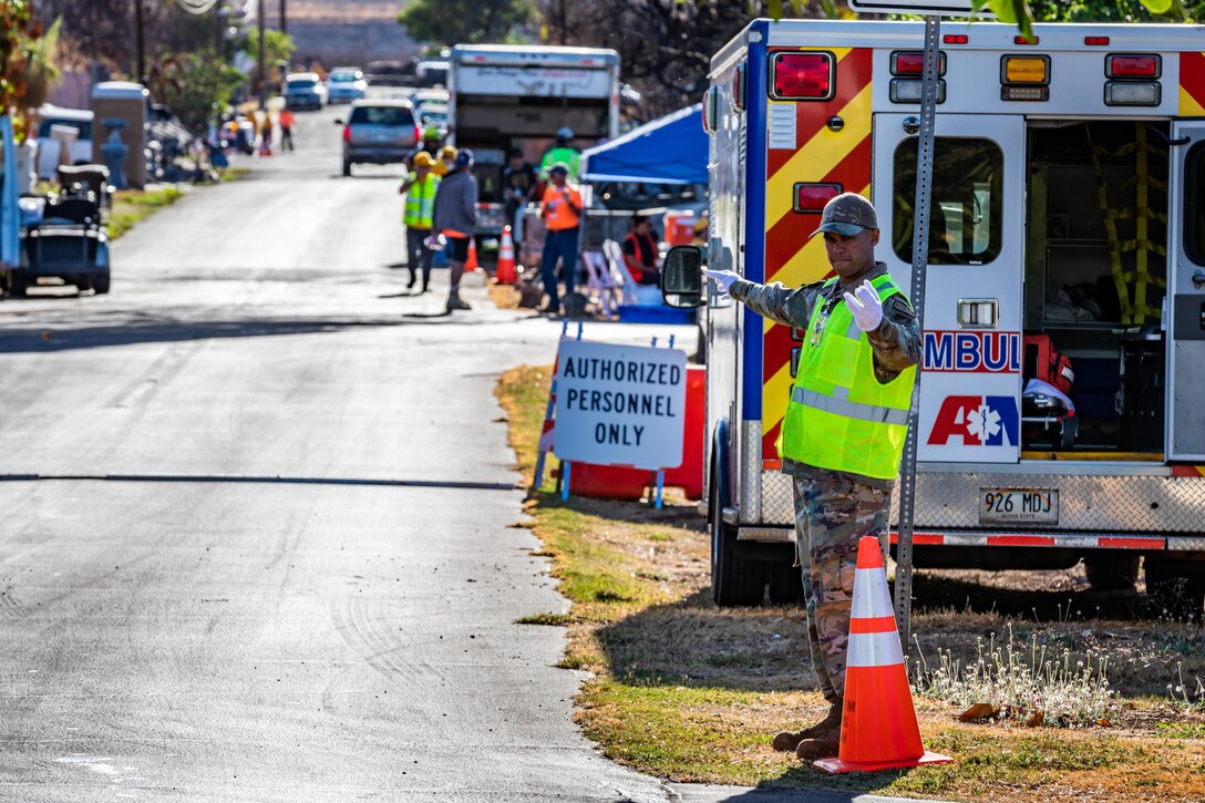 An airman directs community members who are authorized to return to their residences.