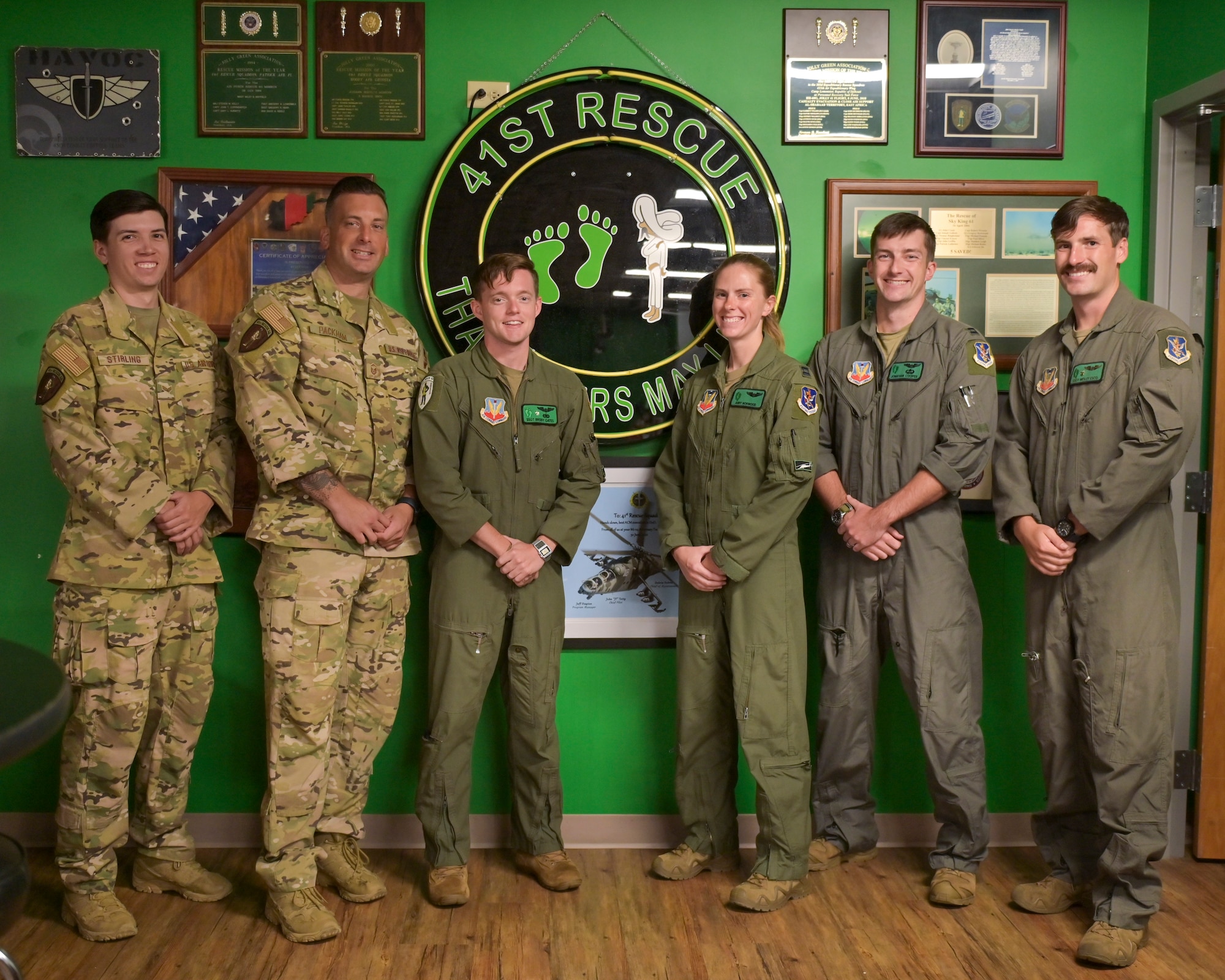 Crew of the HH-60W Jolly Green II stand in front of the 41st Rescue Squadron logo at Moody Air Force Base, Georgia, July 25, 2023. These Airmen were recognized for saving two lives during a rescue mission while on combat deployment in Africa in 2022. (U.S. Air Force photo by Airman 1st Class Leonid Soubbotine)