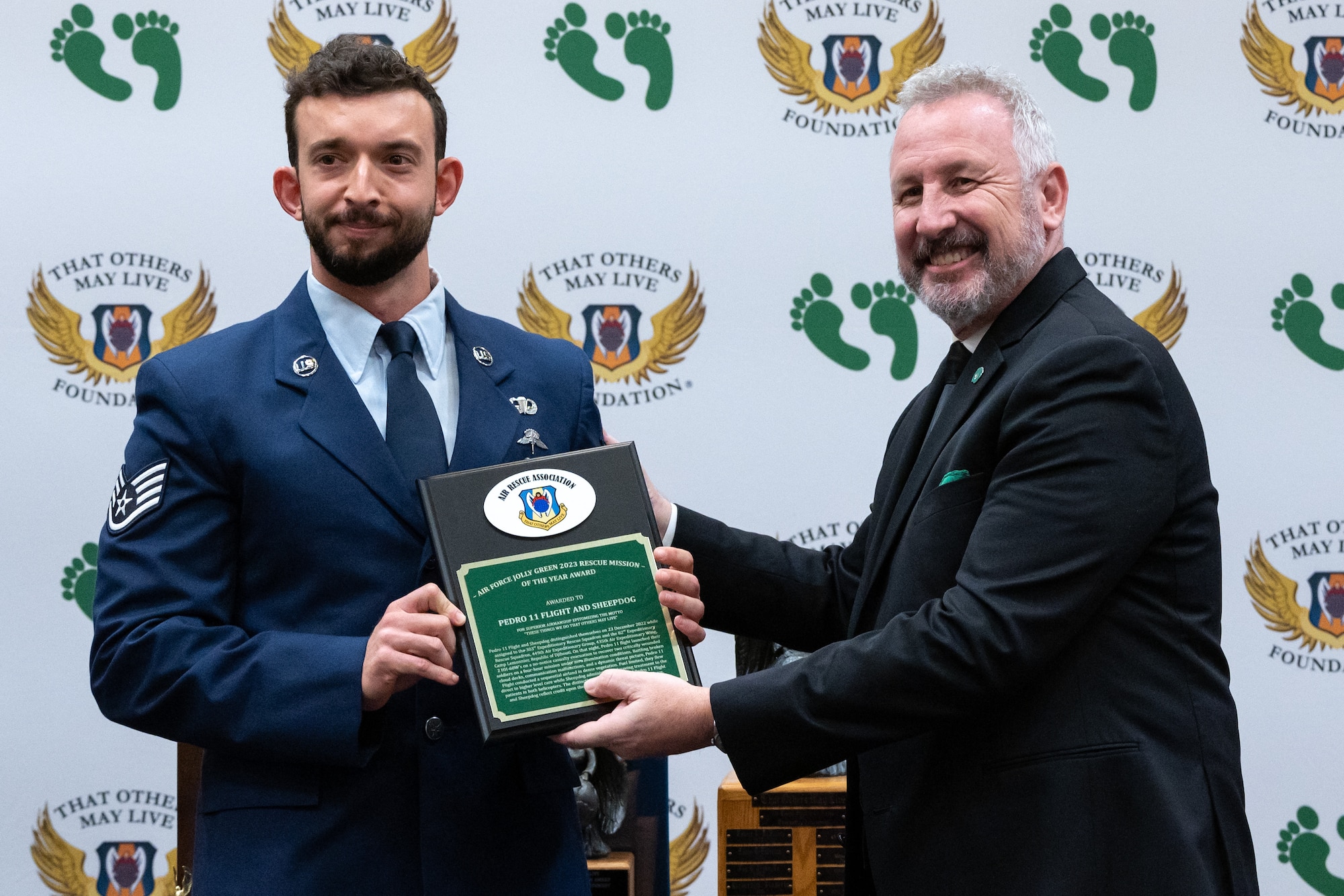 Chris Barnett, right, president of the Air Rescue Association, presents the 2023 Jolly Green Association Mission of the Year award to U.S. Air Force Staff Sgt. Walker Flynn, assigned to the 38th Rescue Squadron Pararescue Team at the 2023 Air Rescue Awards Gala in Las Vegas, Nevada, Sept. 23, 2023. Staff Sgt. Flynn accepted the award on behalf of Pedro 11 Flight and Sheepdog assigned to the 38th Rescue Squadron, 347th Rescue Group, 23rd Wing, from Moody Air Force Base, Georgia. Pedro 11 Flight and the pararescue team, call sign, Sheepdog, distinguished themselves during their assignment to Camp Lemonnier, Republic of Djibouti. During extreme and unfortunate circumstances, Pedro 11 Flight conducted a sequential airland in dense vegetation with limited fuel while Sheepdog administered lifesaving treatment to patients in both helicopters. (U.S. Air Force photo by Airman 1st Class Elizabeth Tan)