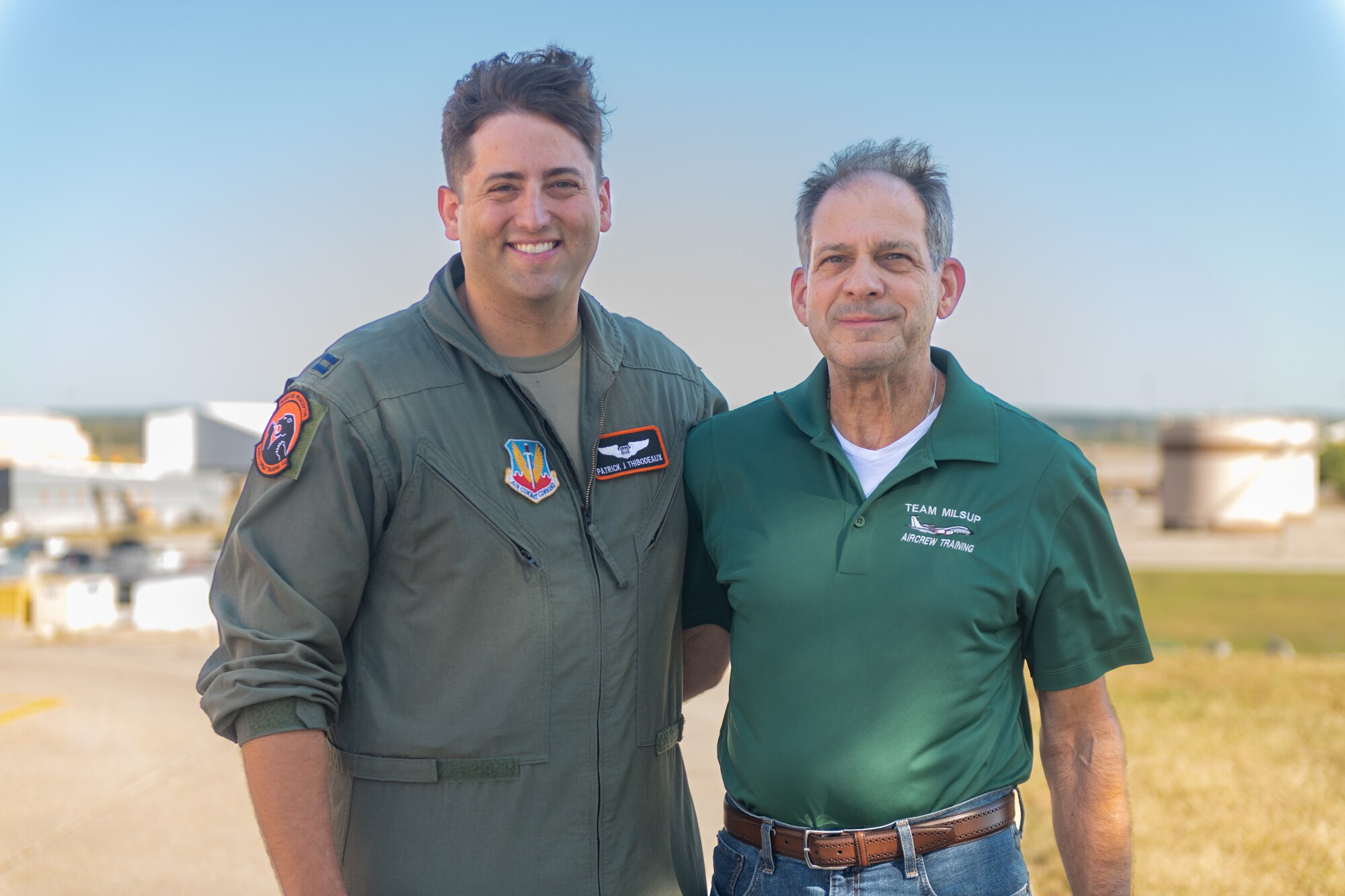 Two men pose for photo.