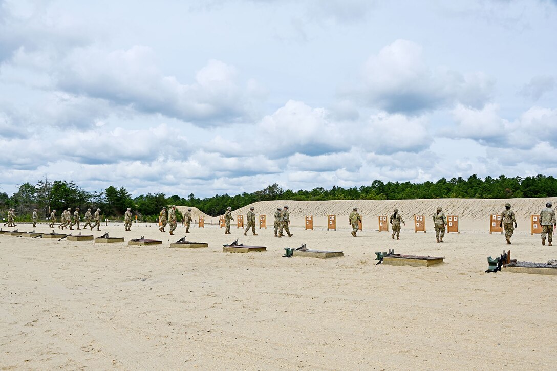 Soldiers walk toward shooting range targets on a sandy area.