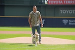 Jay Wilson, a retired Wisconsin Army National Guard lieutenant colonel, looks on as his service dog Frosty carries the ceremonial first pitch to home plate Sept. 17 to start a Milwaukee Brewers™ game at American Family Field™ in Milwaukee.