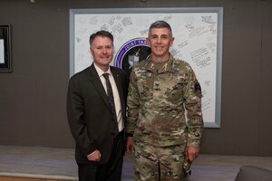 Man in suit and man in military uniform pose for a photo together