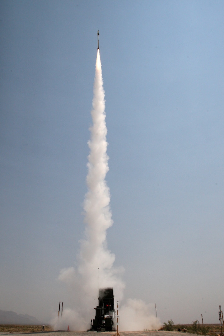 A missile shoots straight up leaving behind a trail of vapor and smoke.