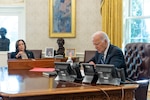 President Joe Biden and Vice President Kamala Harris across from each other at a desk in front of three telephones.