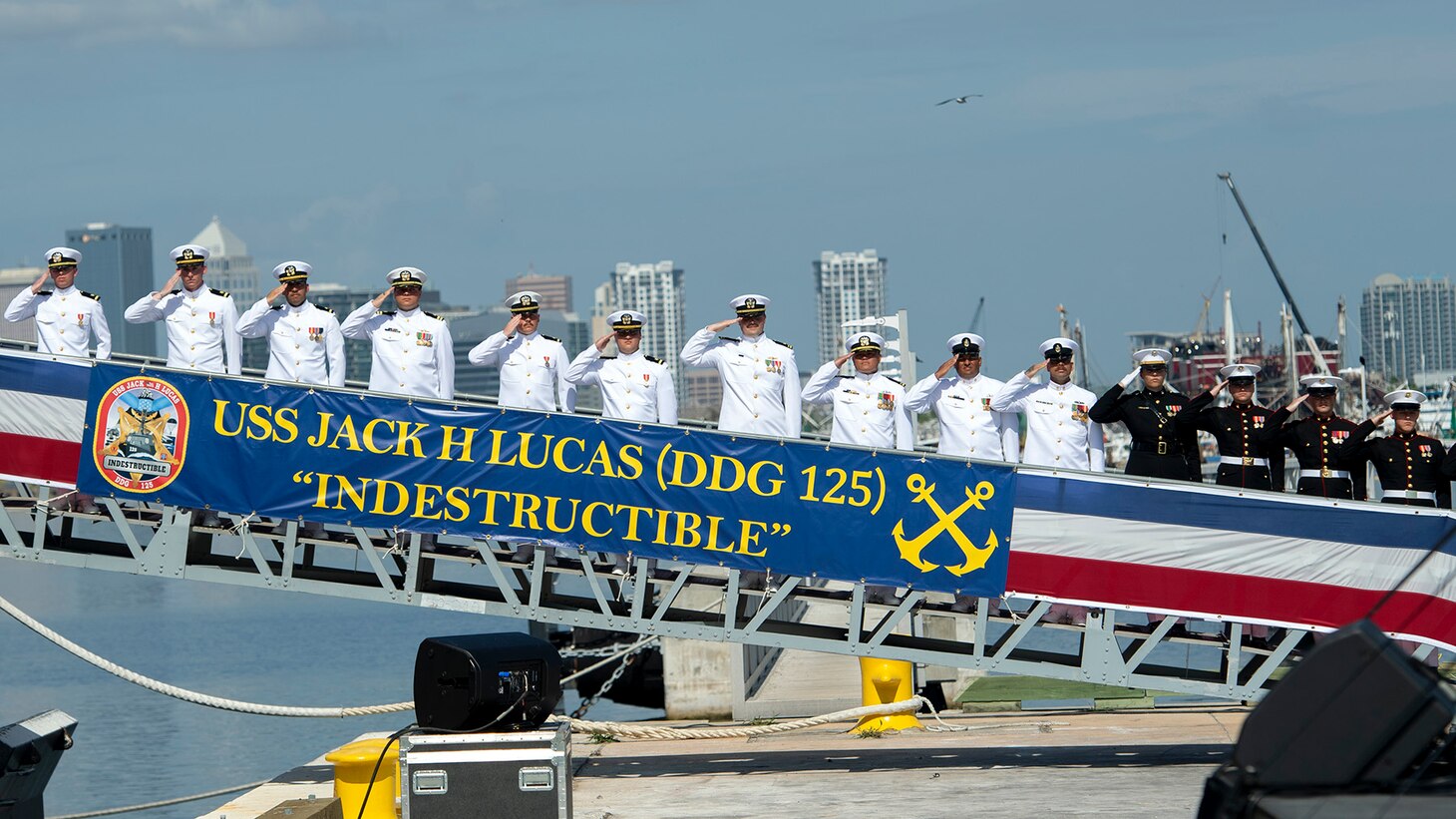 Sailors and U.S. Marines salute during the commissioning ceremony for the Arleigh Burke class Flight III guided-missile destroyer USS Jack H Lucas (DDG 125) in Tampa, Florida Oct. 7, 2023.