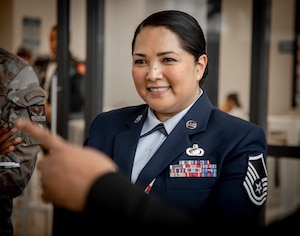 A woman in U.S. Air Force service dress smiles at someone off screen during conversation.