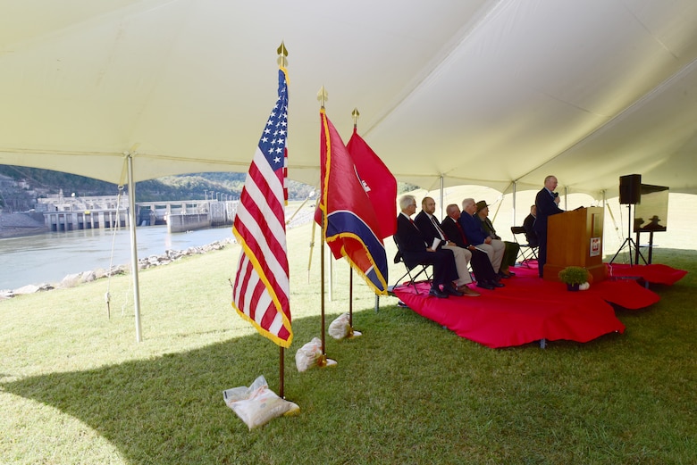 With Cordell Hull Dam in the background, Rep. John Rose, Tennessee 6th District, gives the keynote address while addressing guests during the dam’s 50th Anniversary celebration Oct. 7, 2023, on the shoreline below the dam in Elmwood, Tennessee. He noted that celebrating the achievements of the engineers and the contractors, and public policy makers of the time, made this project possible. (USACE Photo by Lee Roberts)