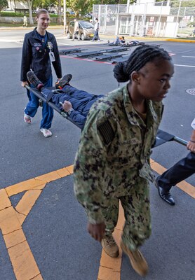Sailors from USNMRTC Yokosuka carry simulated patients into the Emergency Room to be treated during the multi-day, joint-partner Mass Casualty Incident (MDI) training exercise held on October 3-5, 2023.