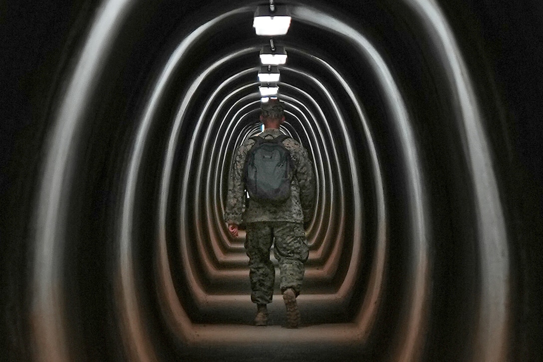 A Marine walks through a tunnel.