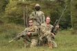 Pennsylvania Army National Guard Soldiers, Sgt. Alexander Tormos (left) and Sgt. Dalton Weist (right), pose with their Lithuanian Land Forces teammate (standing) during the European Best Sniper Team competition at the Joint Multinational Readiness Center near Hohenfels, Germany, Oct. 7, 2023. (U.S. Army photo by Cpl. Eric Perez)