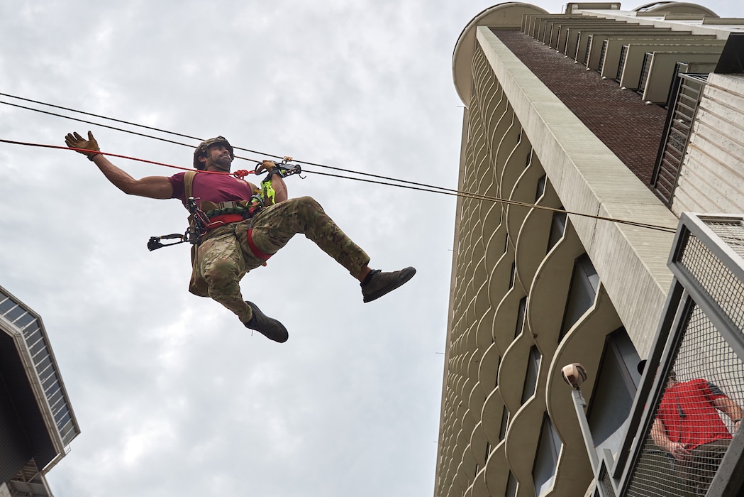 A U.S. Air Force pararescueman executes an urban high-angle ropes scenario to reach a simulated injured service member, render medical care, and lower him to safety during the PJ Rodeo competition in Louisville, Ky., Sept. 6, 2023. The biennial event, which tests the capabilities of pararescue Airmen across the service, was hosted by the Kentucky Air National Guard’s 123rd Special Tactics Squadron. (U.S. Air National Guard photo by Phil Speck)