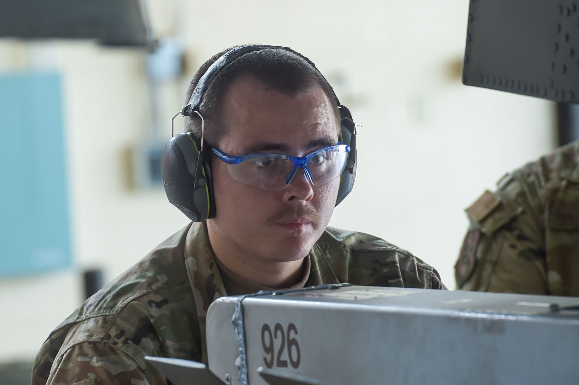 An Airman wear goggles and ear protection while loading munitions onto an aircraft.