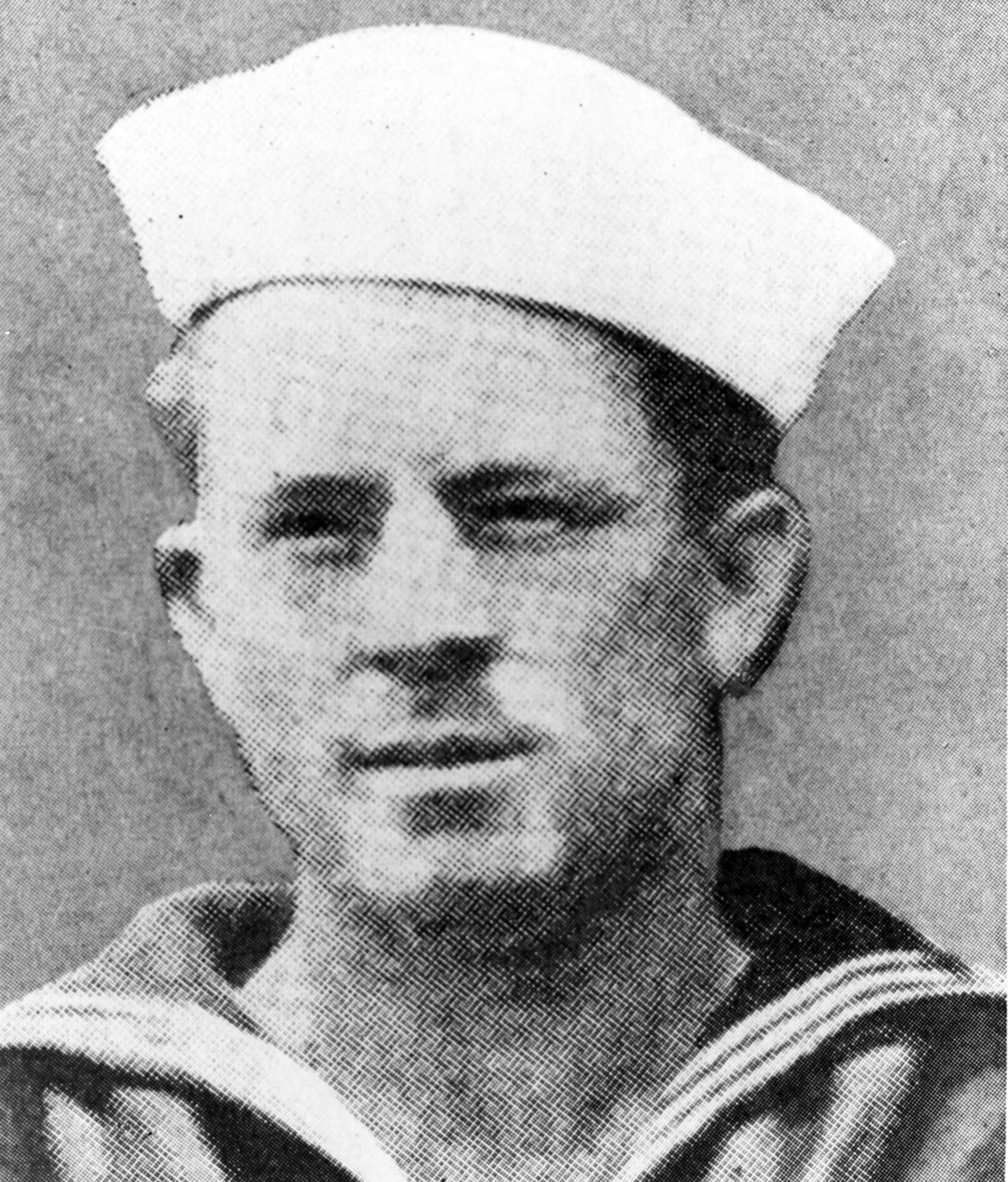 A person in a white sailor’s cap poses for a black and white photo.