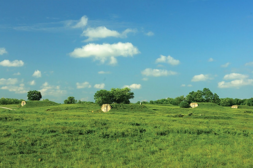 Grass grows over concrete igloos in a field.