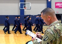 Soldier with clipboard inspects cadets.