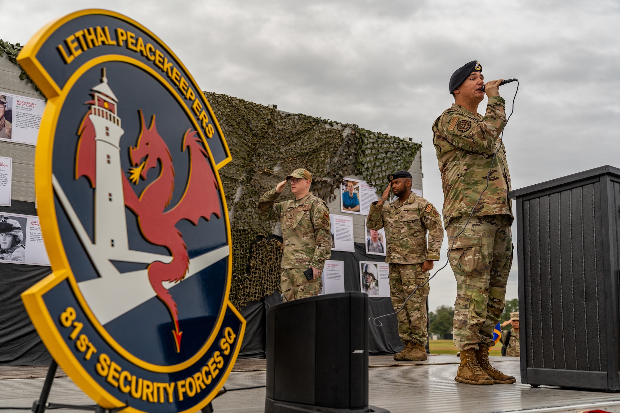 U.S. Air Force Senior Airmen Jordan Ellis, 81st Security Forces Squadron military working dog handler, sings the National Anthem while Capt. Russell Ward II, 81st Training Wing chaplain, and Tech. Sgt. Michael Taku, 81st SFS flight sergeant, salute before the 2023 Fallen Defender Ruck at Keesler Air Force Base, Mississippi, Oct. 6, 2023.