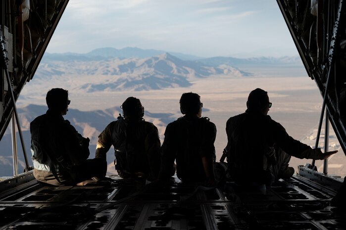 U.S. Air Force Airmen from the 34th Weapons Squadron (WPS) look out the back of a C-130J Combat King II over Las Vegas, Nevada, Oct. 9, 2023.