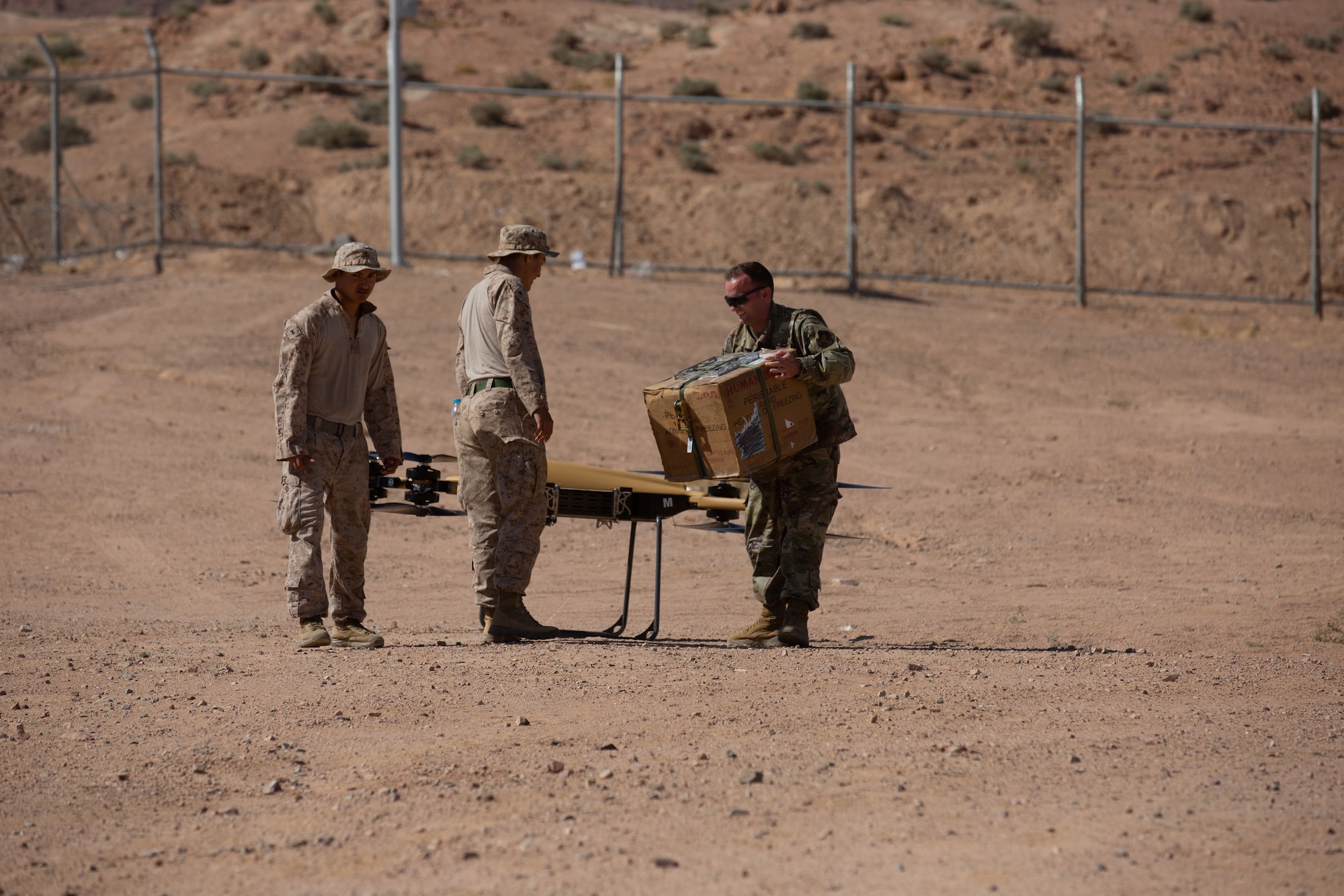 U.S. Air Force and Marine members attach cargo to an UAV