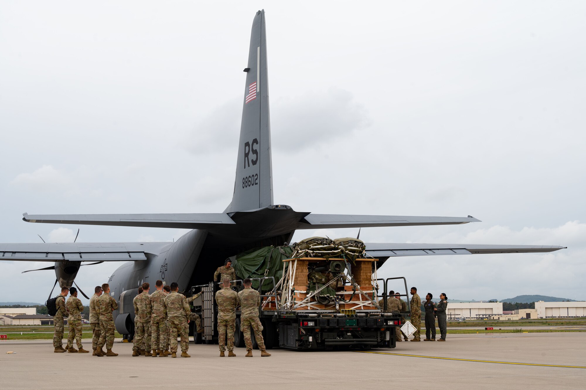 Airmen and soldiers load a 32 foot-long cargo pallet with ammo onto a C-130