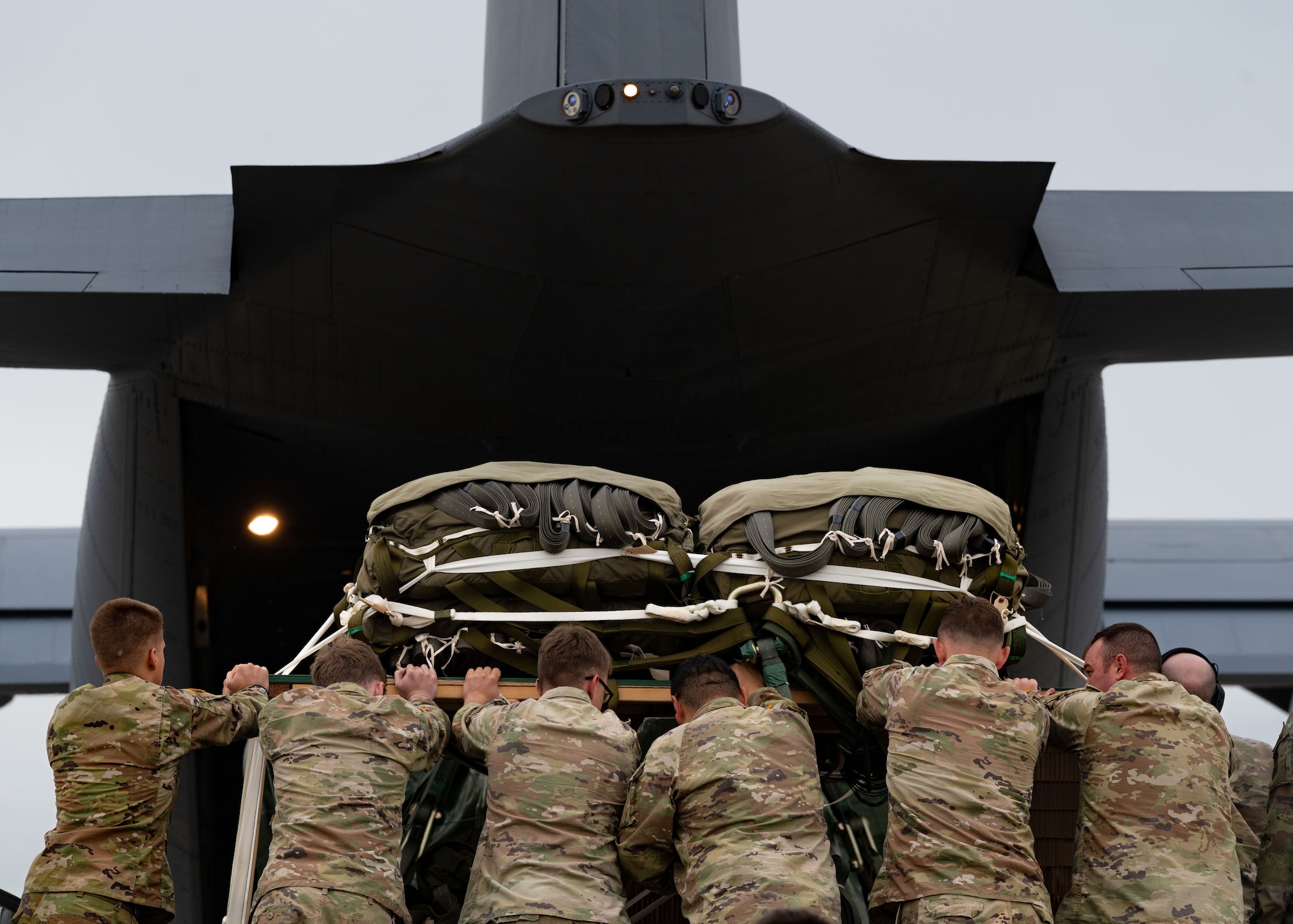 Airmen and Soldiers push an ammo pallet into a C-130 aircraft