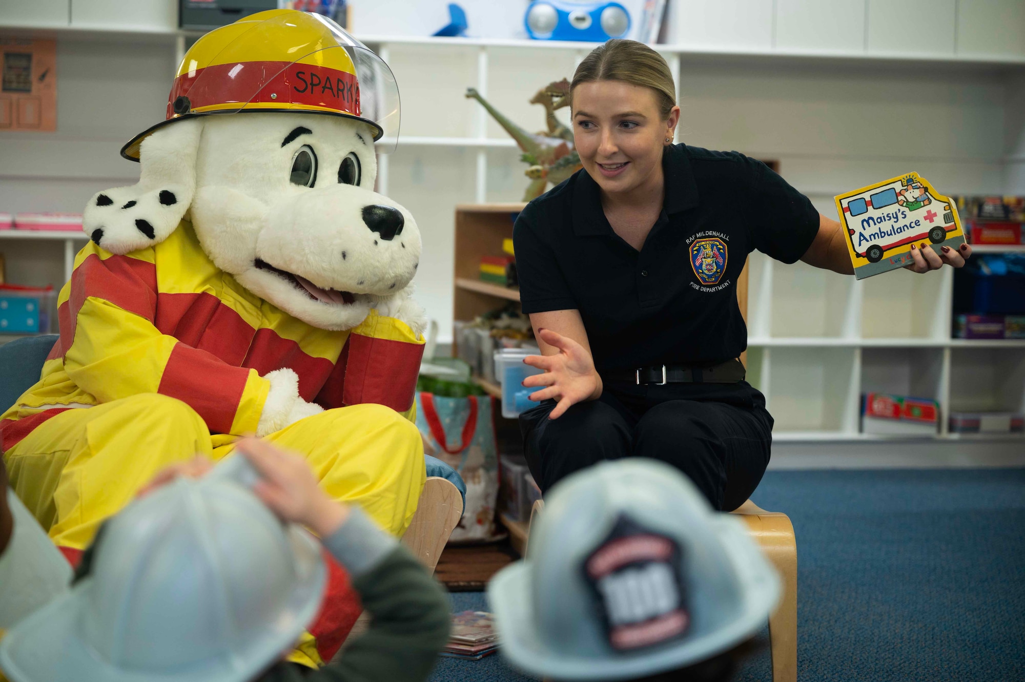 Danielle Petham, 100th Civil Engineer Squadron Fire Department dispatcher, smiles after reading a book about fire safety to a pre-school class at the 100th Force Support Squadron Child Development Center, Royal Air Force Mildenhall, England, Oct. 11, 2023. As part of fire prevention week, Sparky the Fire Dog and members of the 100th CES educated children about fire safety, protecting military families and increasing morale. (U.S. Air Force photo by Senior Airman Viviam Chiu)