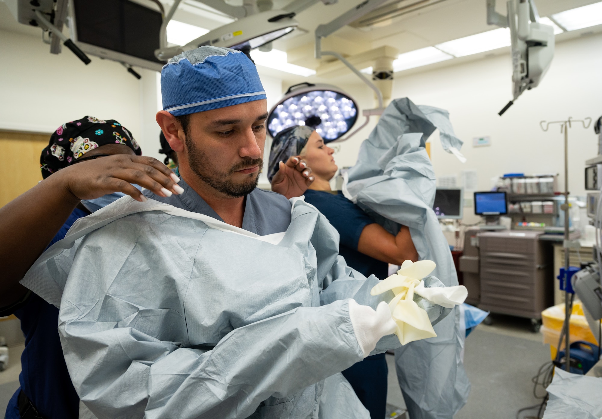 A male Airman dons his gown and gloves while a female Airman does the same on the right