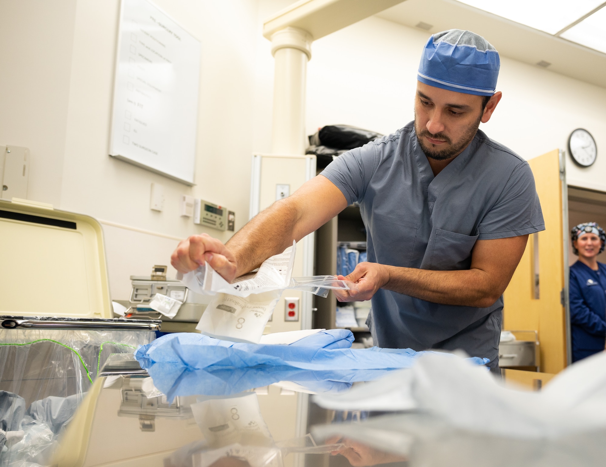 A male Airman in scrubs opens a packet