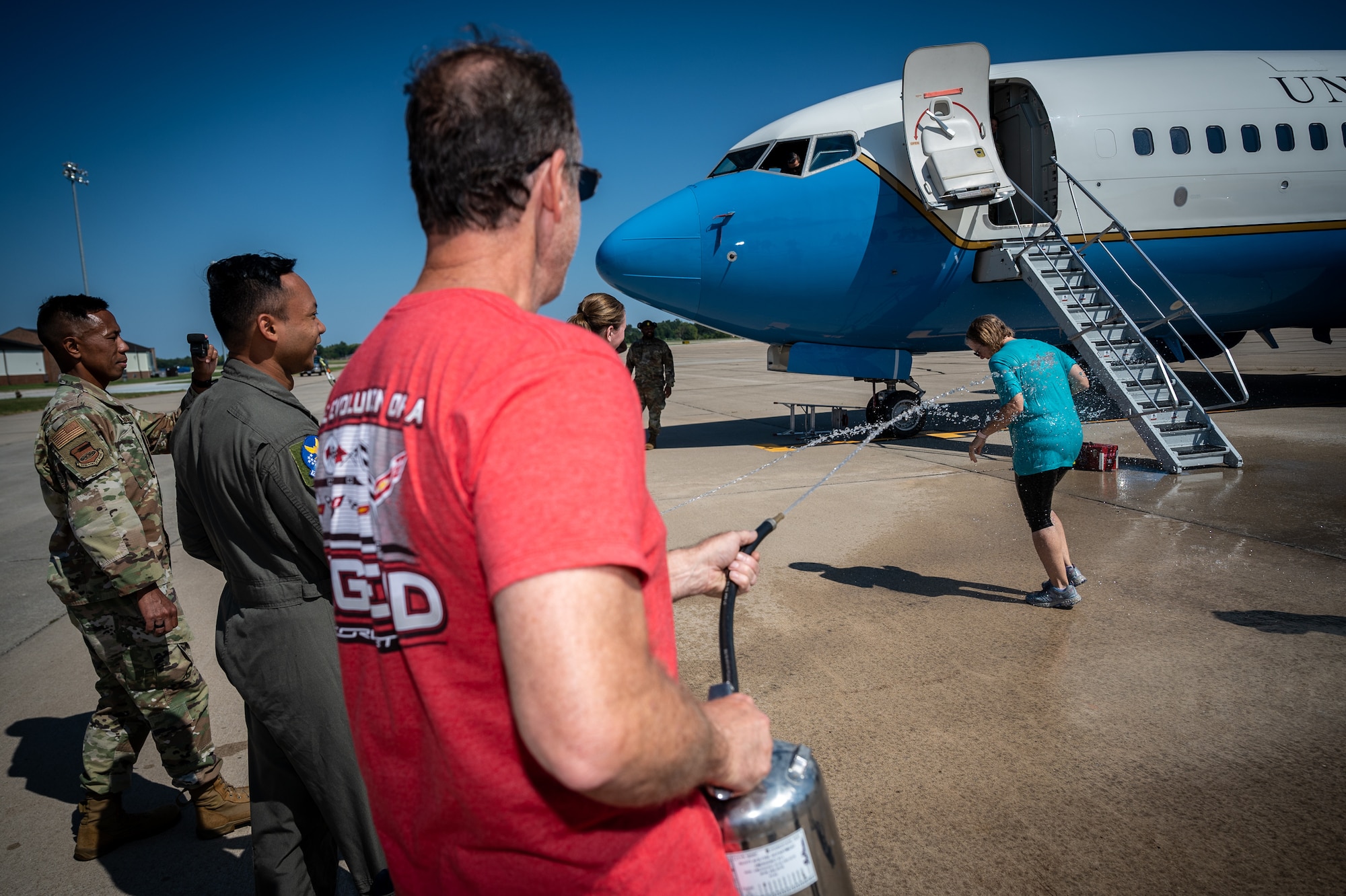 Deb Teague is hosed down by her husband and friends from the 932nd Airlift Wing following her fini flight and combined incentive flight Oct. 9, 2023, Scott Air Force Base, Illinois. After over 15 years of civilian service, the 932nd Military and Family Readiness Center program manager closed her Air Force career, which originated from active duty military service at the age of 19. (U.S. Air Force photo by Christopher Parr)