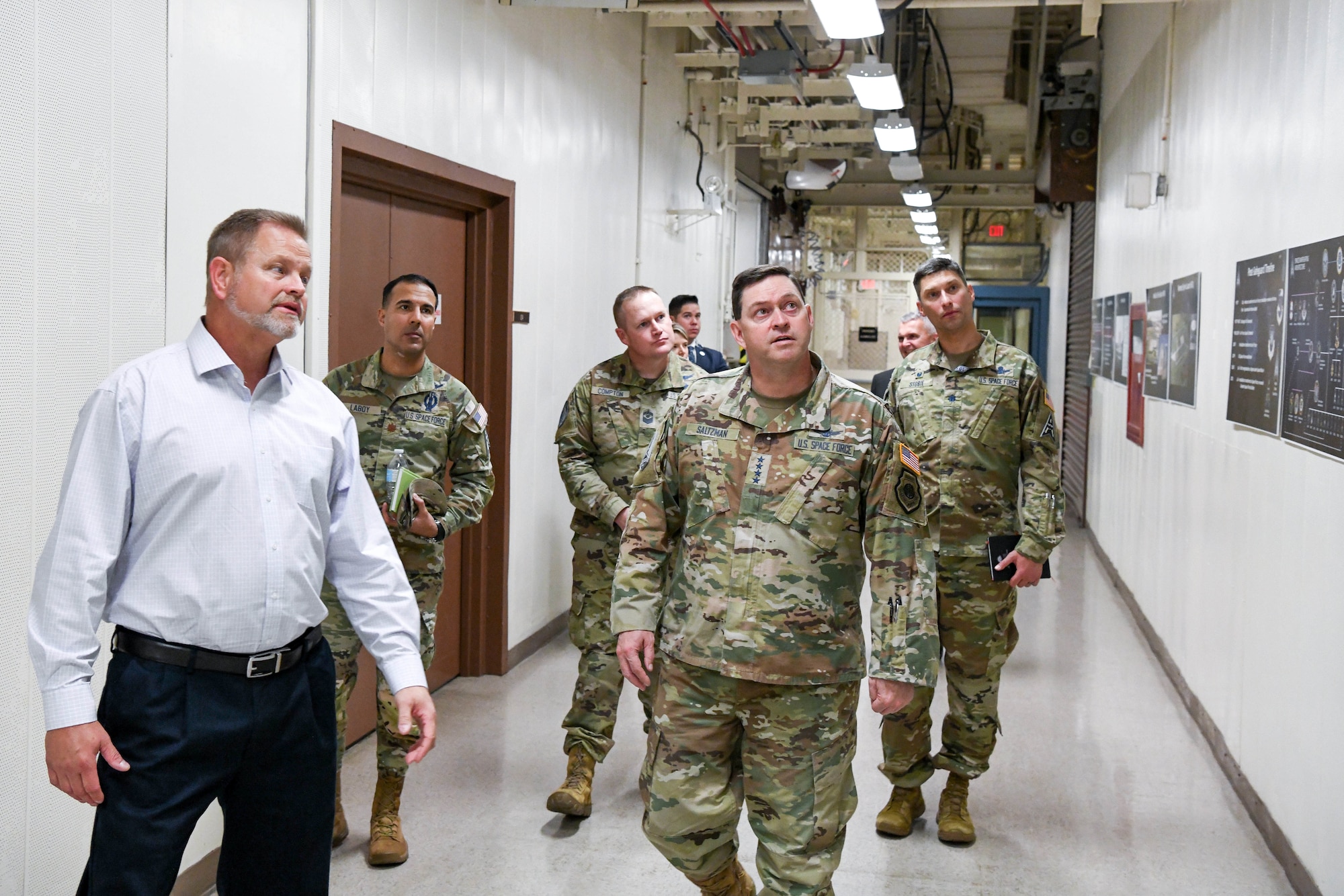Four star military general walks with a group of military members.