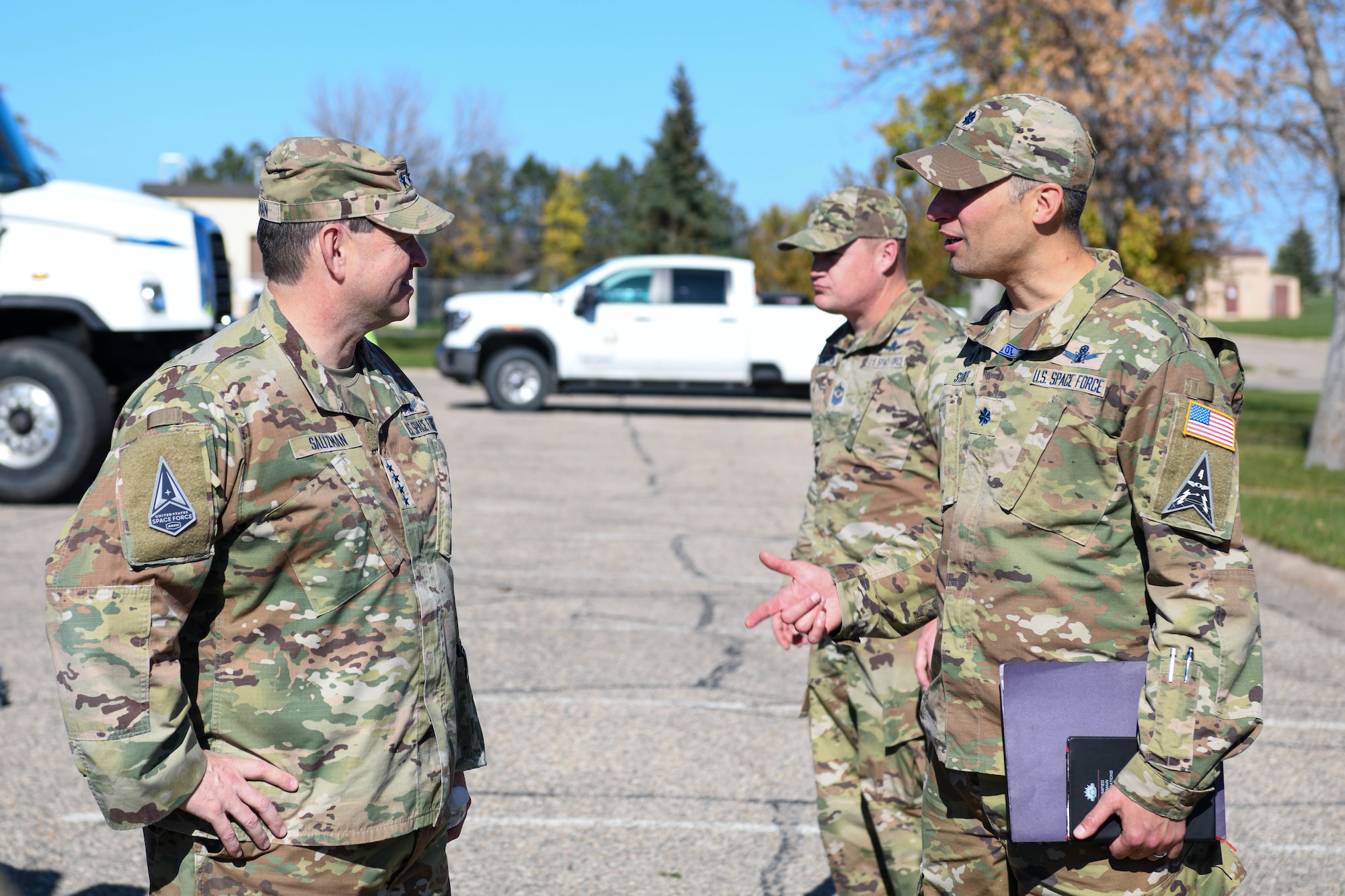 Two men in military uniforms talk while outside.
