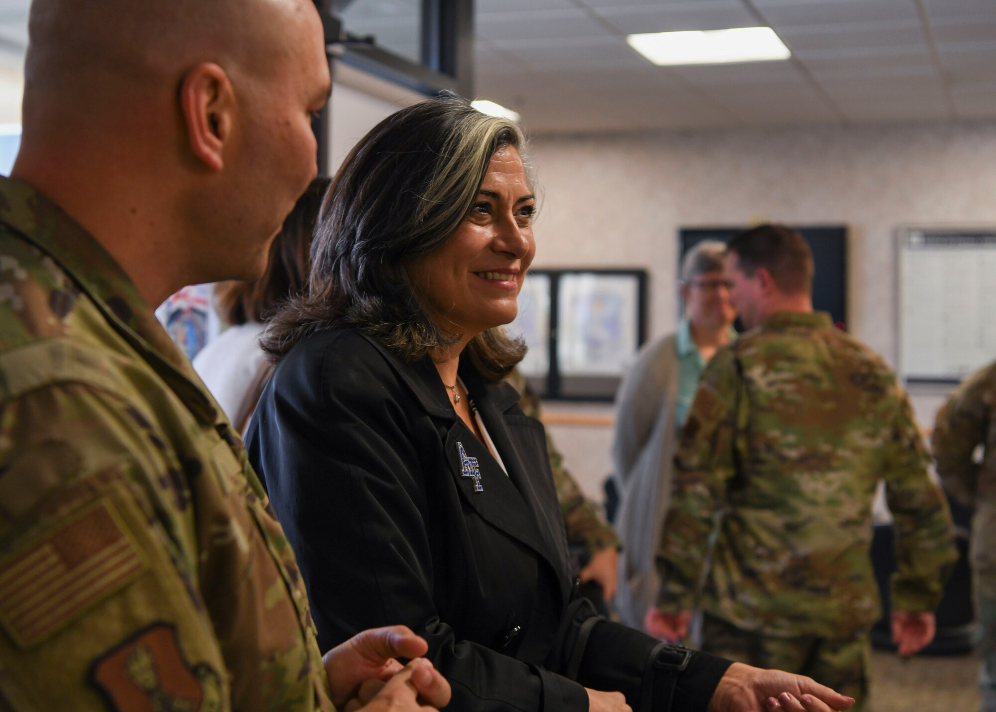 A woman and a man in a green uniform stand next to each other.