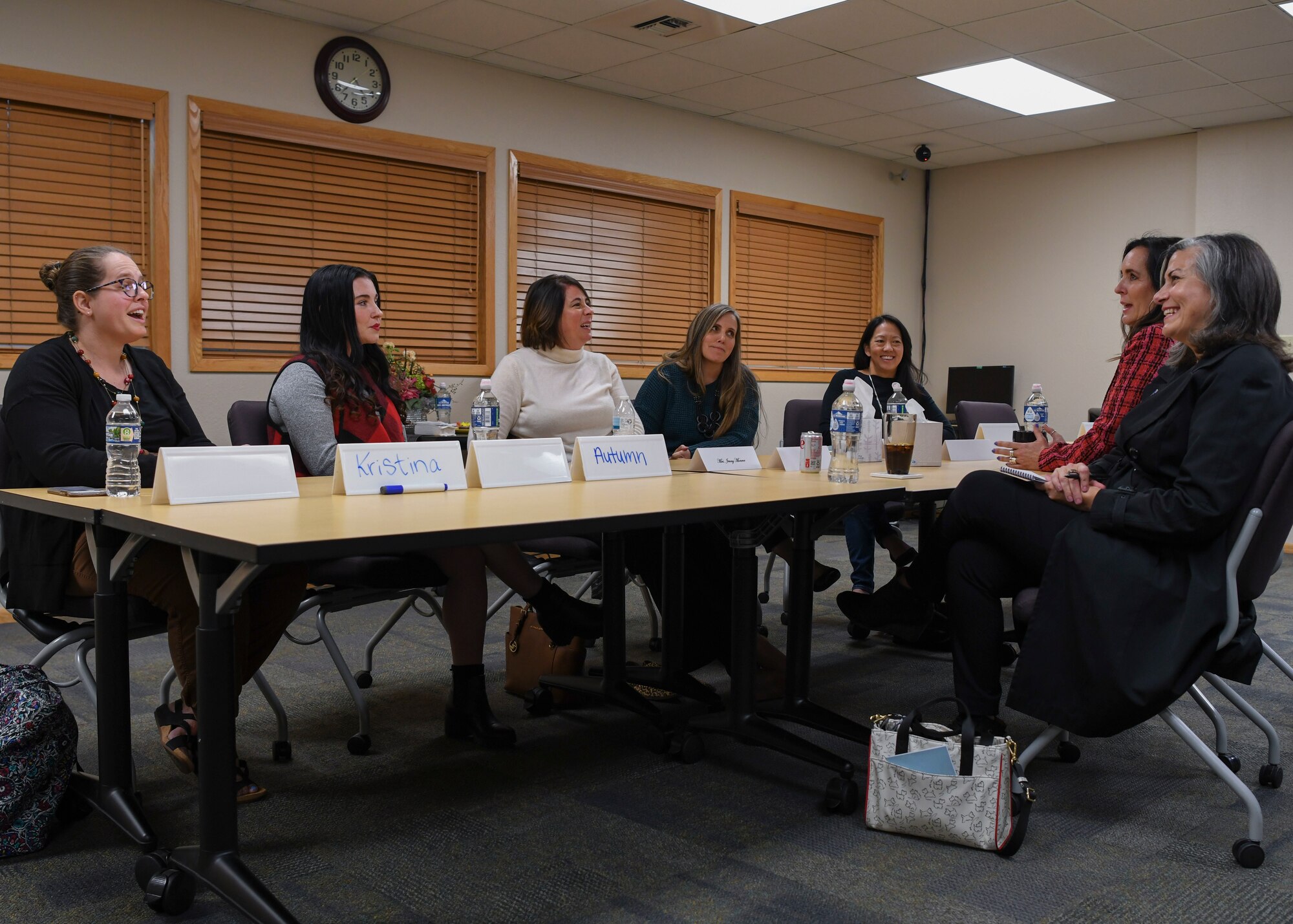 Several women sit around a table talking.