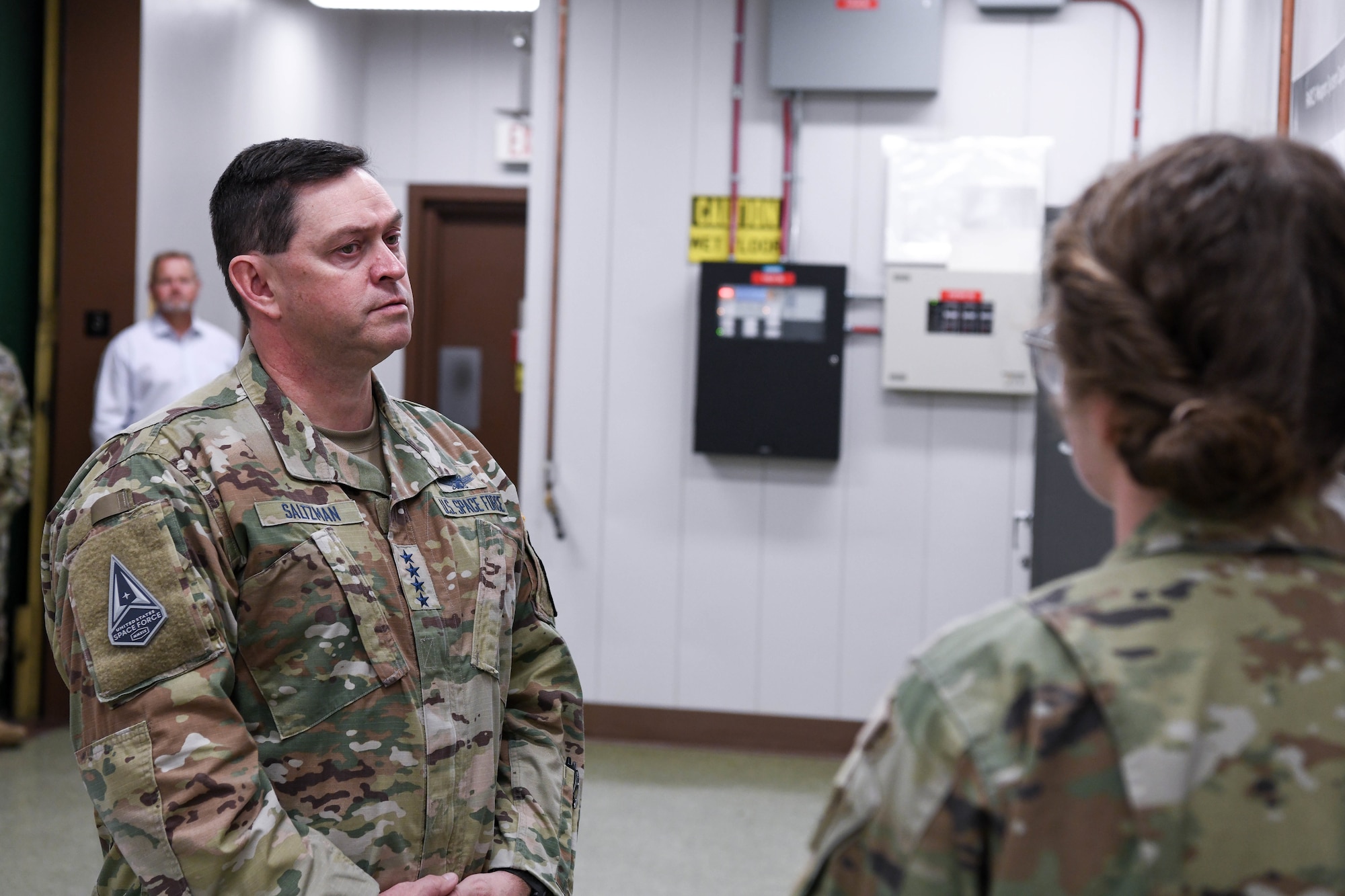 Four star military general listens while another military member speaks.