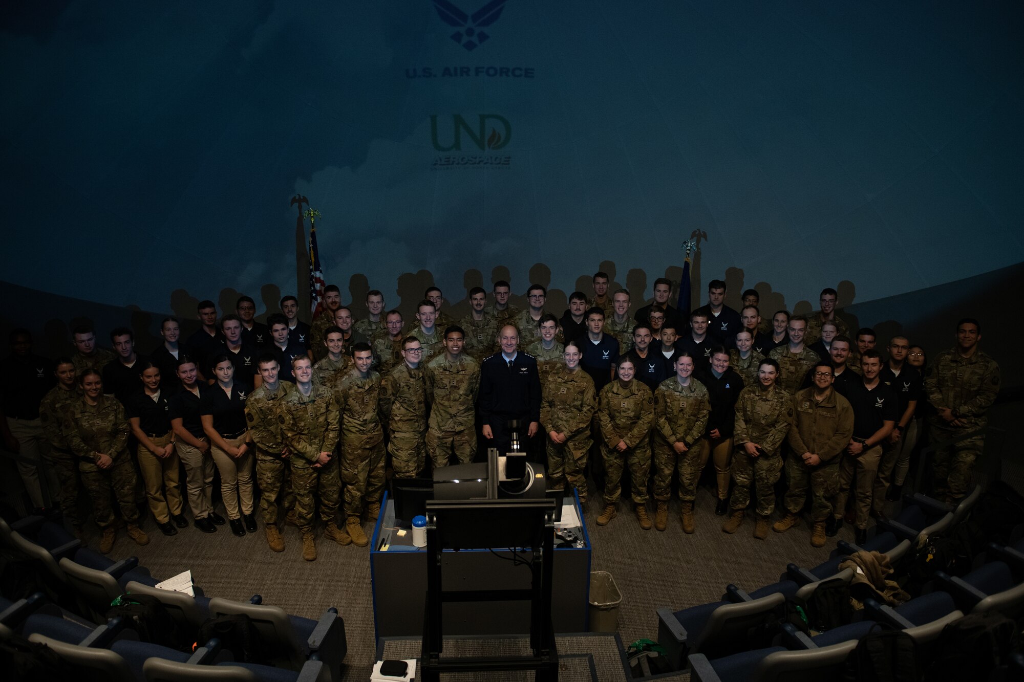 Military ROTC cadets pose with a service member for a camera photo.