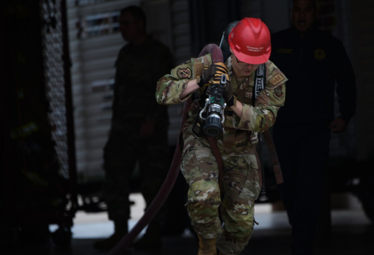 An Airman from the 22nd Munitions Squadron drags a fire hose during the annual 22nd Civil Engineer Squadron Fire Muster Oct. 12, 2023, at McConnell Air Force Base, Kansas. The Fire Muster consisted of five teams competing for the fastest time to complete various tasks such as climbing a ladder, unrolling a large fire hose, dragging a dummy and spraying a fire hose at a target. (U.S. Air Force photo by Staff Sgt. Tryphena Mayhugh)