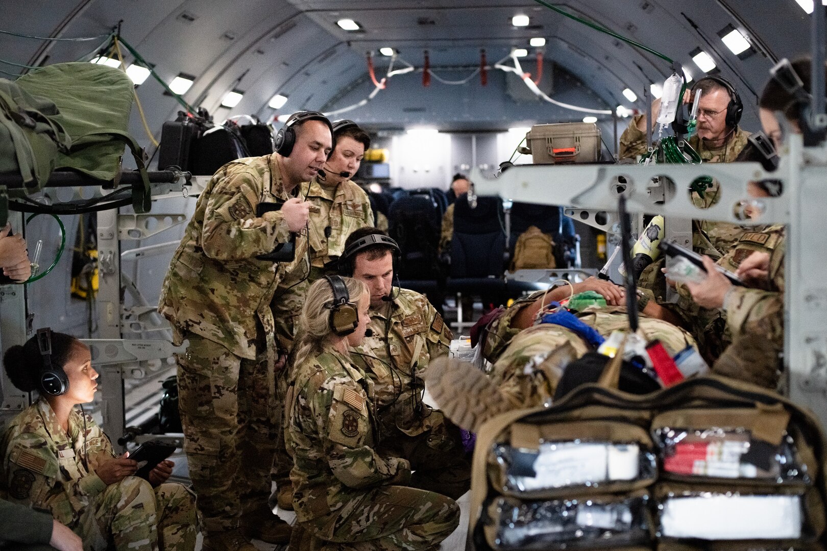 Airmen gather around a simulated patient for a lesson during a training flight