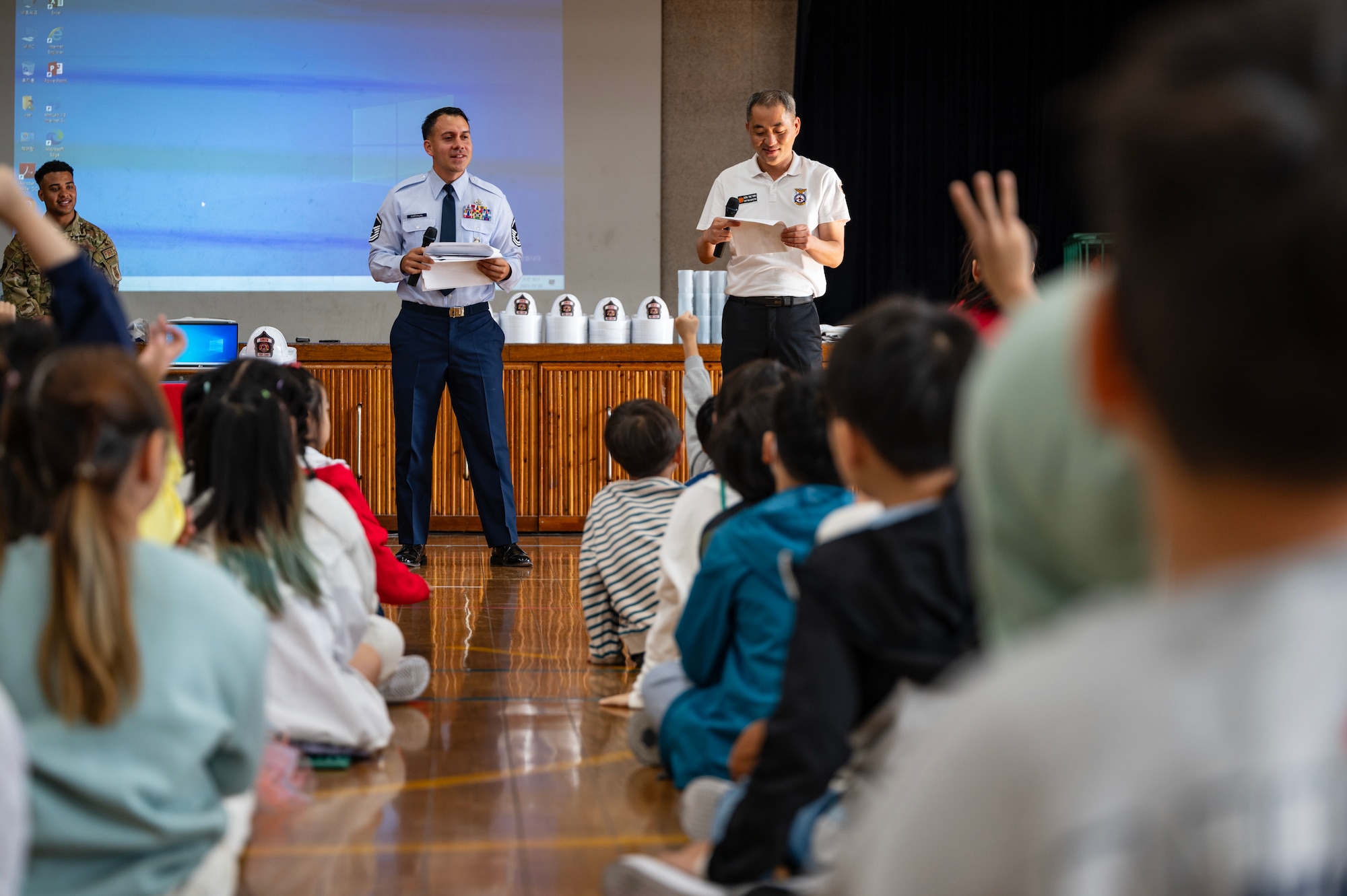 Master Sgt. Carlos Carvajal and Tae Yon Kim brief students on fire safety habits during a Fire Prevention Week educational event.