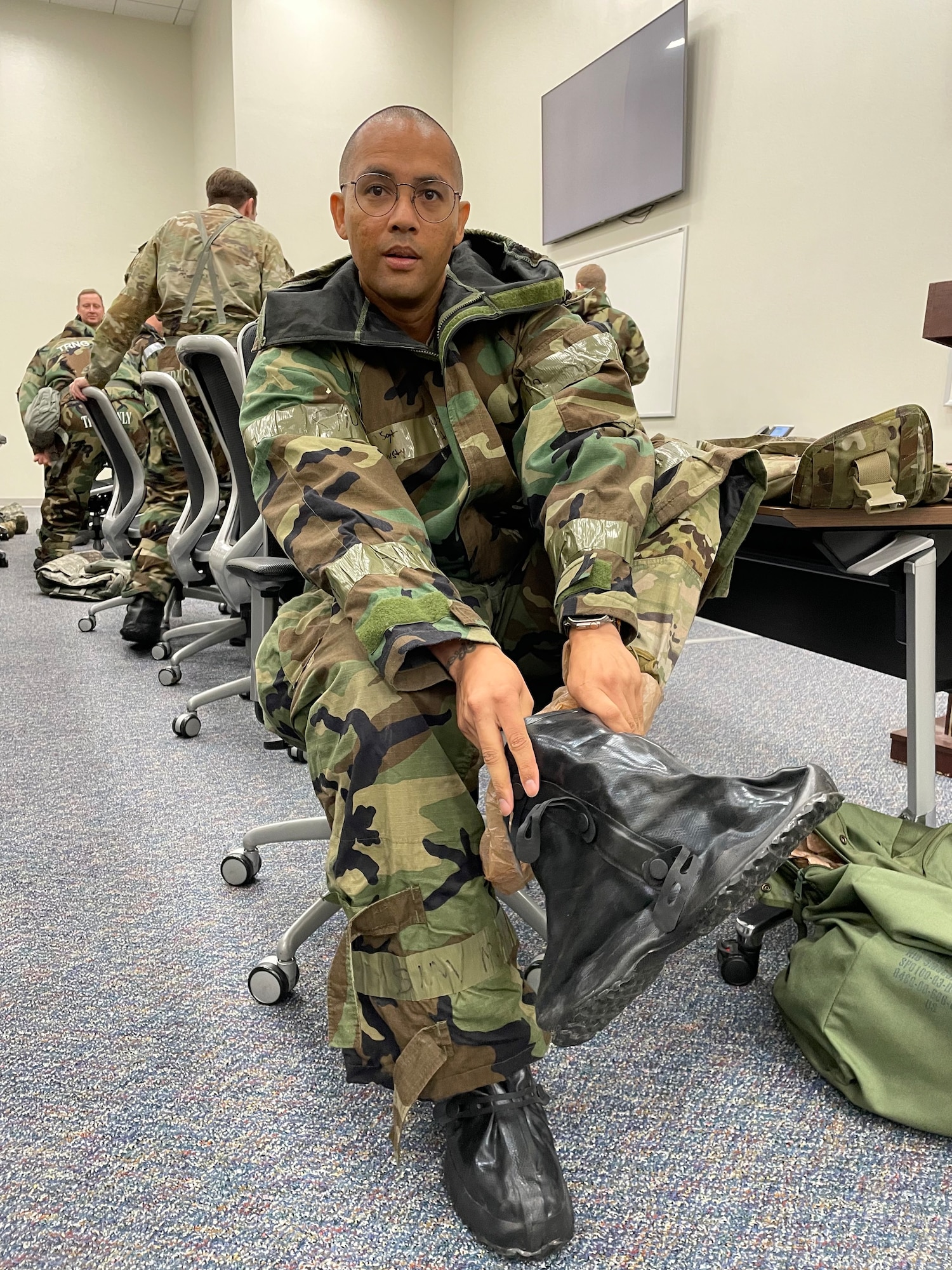 a soldier dressed in protective gear, working on a rubber over boot