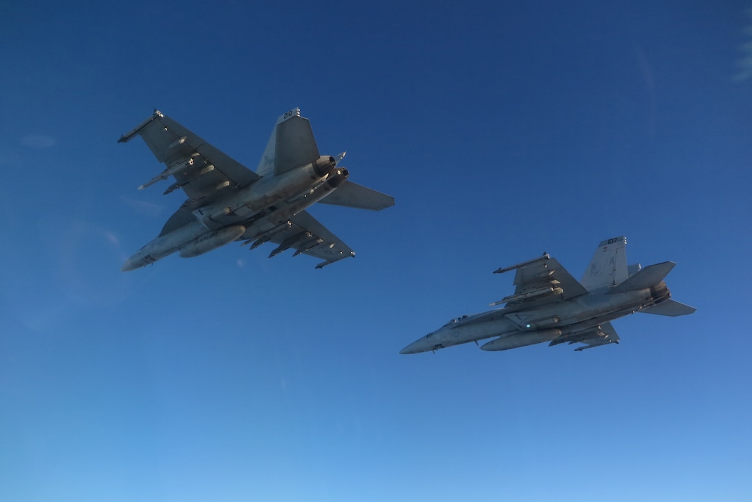 An F/A-18F Super Hornet, left, and an F/A-18E Super Hornet fly in formation.