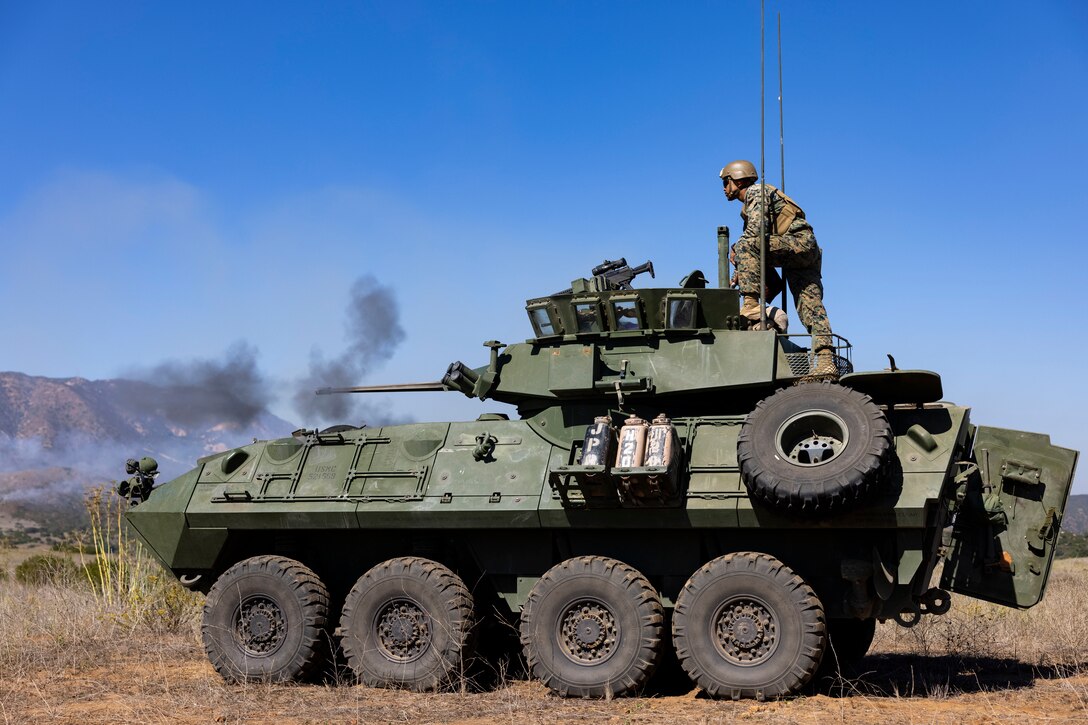 A large armored vehicle fires a cannon at a target.