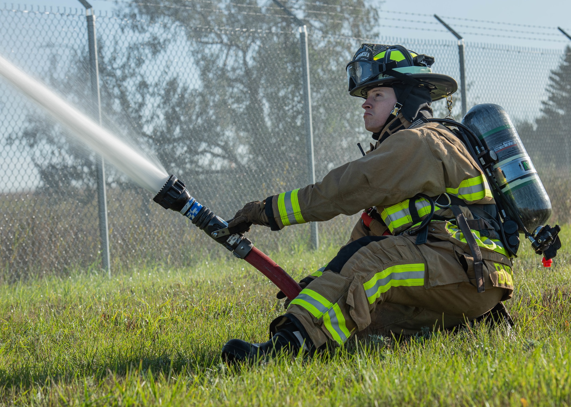 Airman 1st Class Cole Burchfield, 5th Civil Engineer Squadron firefighter, discharges a fire hose during a National Fire Protection Association 1410 drill at Minot Air Force Base, North Dakota, Oct. 4, 2023. Burchfield worked in tandem with his fellow firefighters to successfully and efficiently complete all components of the drill. (U.S. Air Force photo by Airman 1st Class Kyle Wilson)