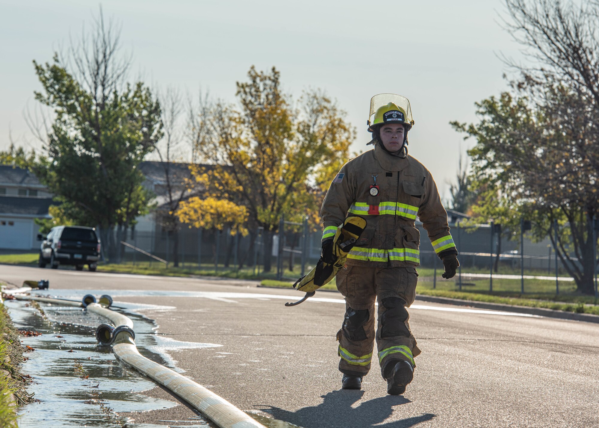 Airman 1st Class Alberto Alvarez, 5th Civil Engineer Squadron firefighter, carries equipment after a National Fire Prevention Association (NFPA) 1410 drill at Minot Air Force Base, North Dakota, Oct. 4, 2023. During the drill, Alvarez was responsible for connecting the fire hose to a fire hydrant and ensuring it was functioning properly. (U.S. Air Force photo by Airman 1st Class Kyle Wilson)