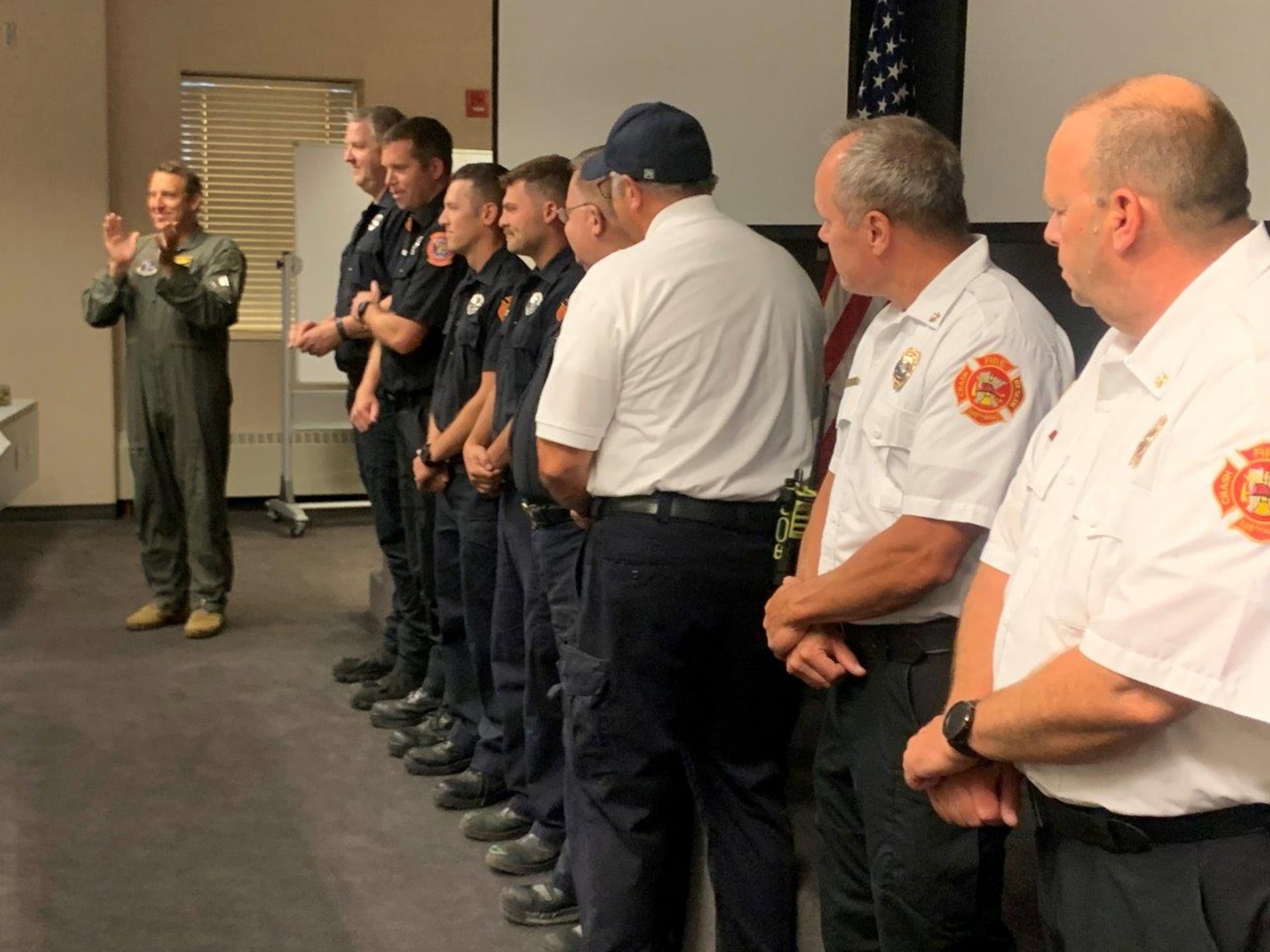 148th Fighter Wing Commander, Col. Nate Aysta, recognizes the crew of Fire Protection Specialists assigned to the 148th Fighter Wing, Minnesota Air National Guard, who responded to two Leap Frog Navy Parachute Team members who released and detached at a lower-than-normal altitude at the Duluth Airshow on July 15, 2023. (U.S. Air National Guard photo by Audra Flanagan)