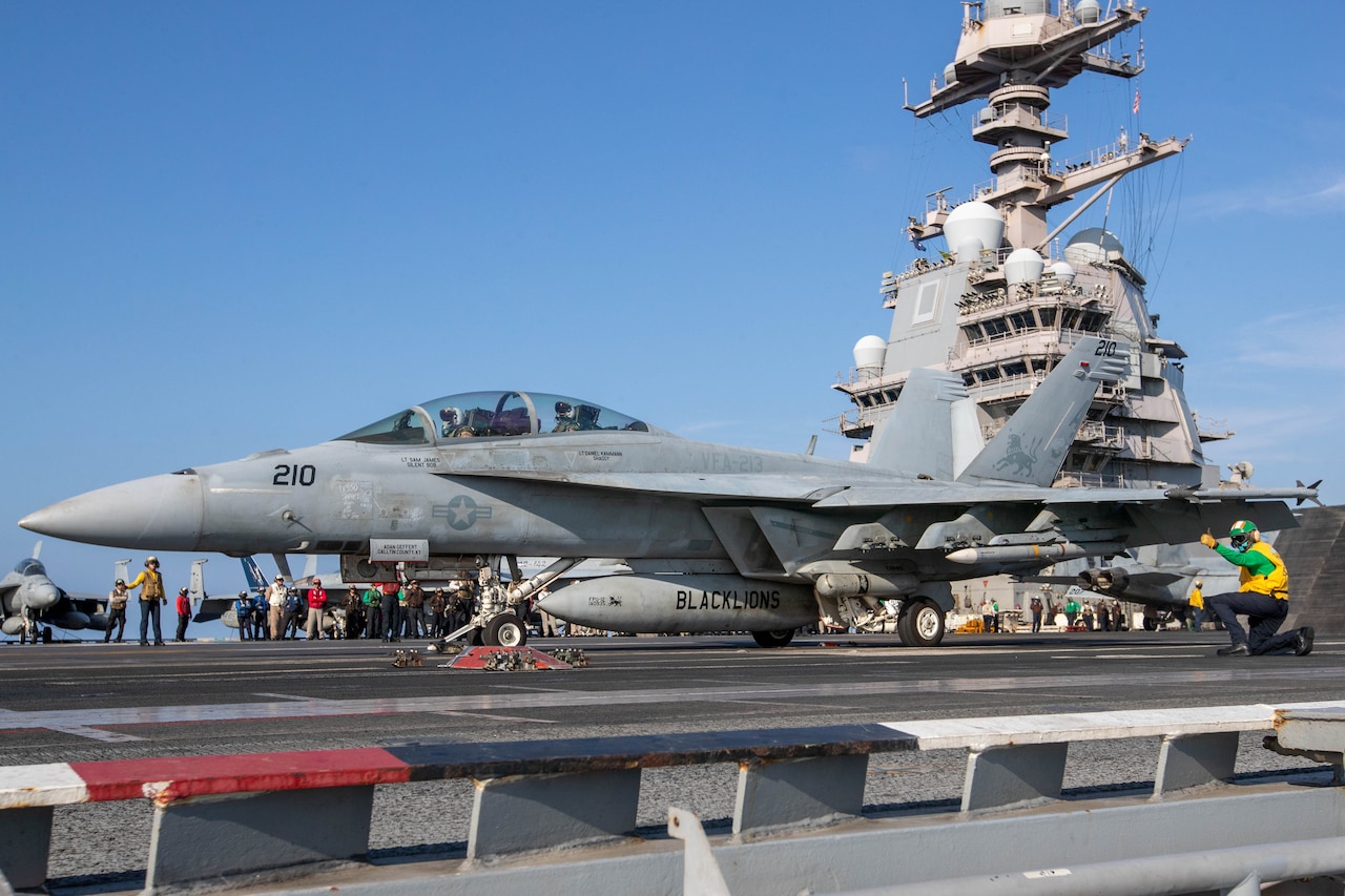 A fighter jet is ready to launch from the flight deck of an aircraft carrier.