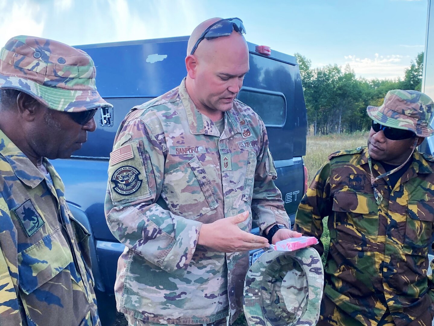 Senior Master Sgt. Erich Sanford discusses C4 and its characteristics with Petty Officer Tivurmei Erengi and Able Seaman Jeremy Magea — Maritime Element members of the Papua New Guinea Defence Force — during an Advanced EOD Conventional Course at Camp Ripley Training Center in Little Falls, Minn.