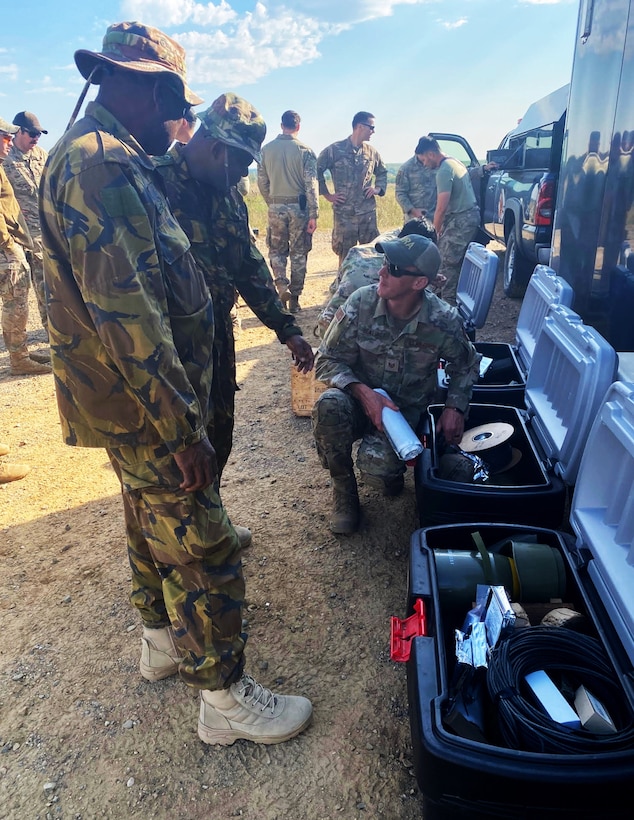 Petty Officer Tivurmei Erengi and Able Seaman Jeremy Magea — Maritime Element members of the Papua New Guinea Defence Force — discuss different ordnance materials with a U.S. Air Force EOD technician during an Advanced EOD Conventional Course at Camp Ripley Training Center in Little Falls, Minn.