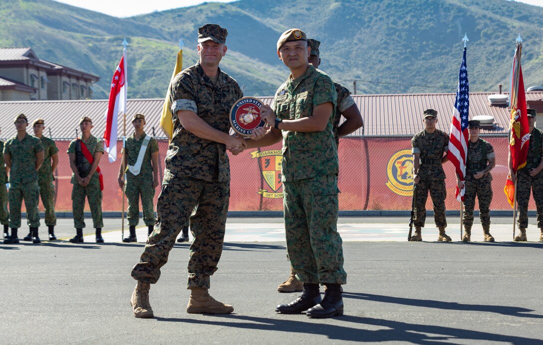 U.S. Marine Corps Col. Stuart Glenn, left, commanding officer of 13th Marine Expeditionary Unit, I Marine Expeditionary Force, and Singapore Armed Forces Senior Lt. Col. Phua Chai Kin, 2nd in command of 7th Singapore Infantry Brigade, exchange gifts during the opening ceremony for Exercise Valiant Mark 2023 at Camp Pendleton, CA, Oct. 7, 2023. Valiant Mark 23 is an annual, bilateral training exercise conducted between the Singapore Armed Forces and I Marine Expeditionary Force, designed to enhance interoperability, improve combined arms and amphibious warfighting skills, and strengthen military-to-military relationships. (U.S. Marine Corps photo by Staff Sgt. Dana Beesley)