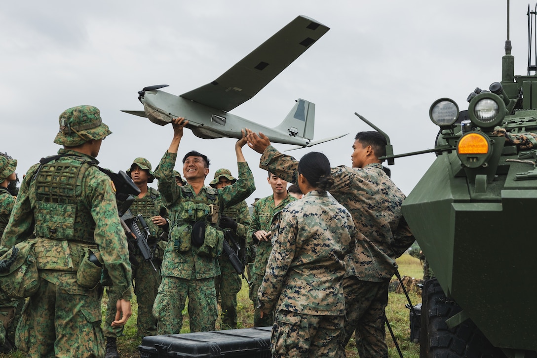 U.S. Marines with 1st Light Armored Reconnaissance Battalion, 1st Marine Division, I Marine Expeditionary Force, demonstrate the capabilities of the RQ-20B Puma to Singapore Guardsmen with 7th Singapore Infantry Brigade, during an unmanned aerial system subject matter expert exchange as part of Exercise Valiant Mark 2023 at Camp Pendleton, CA, Oct. 11, 2023. Valiant Mark 23 is an annual, bilateral training exercise conducted between the Singapore Armed Forces and I Marine Expeditionary Force, designed to enhance interoperability, improve combined arms and amphibious warfighting skills, and strengthen military-to-military relationships. (U.S. Marine Corps photo by Staff Sgt. Dana Beesley)