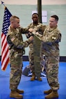 Commanding Officer Lt. Col. Jason Sabovich and Command Sgt. Maj. Chad Weber furls the battalion colors in preparation for the unfurling of the newly established 401st Cyber Battalion's colors as Master Sgt. Quientin Abston holds the staff.